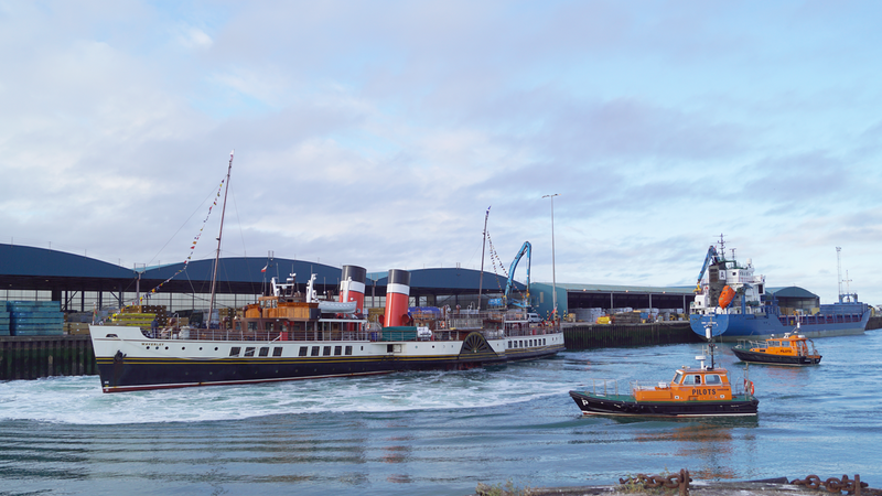 Paddle steamer boat at port with orange pilot boats