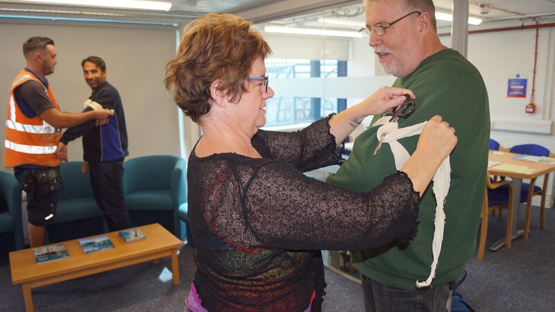 A woman practicing putting a bandage on a mans arm.