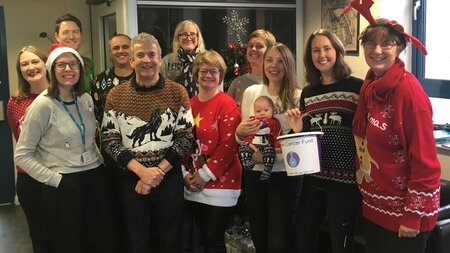 A group of people wearing fun colourful Christmas jumpers.