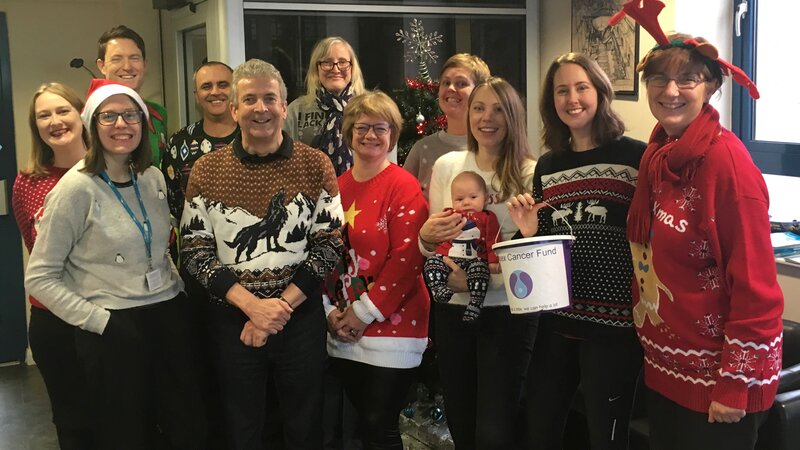 A group of people wearing fun colourful Christmas jumpers.