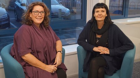 Two women, Nicky and Laura sit on two single sofas.